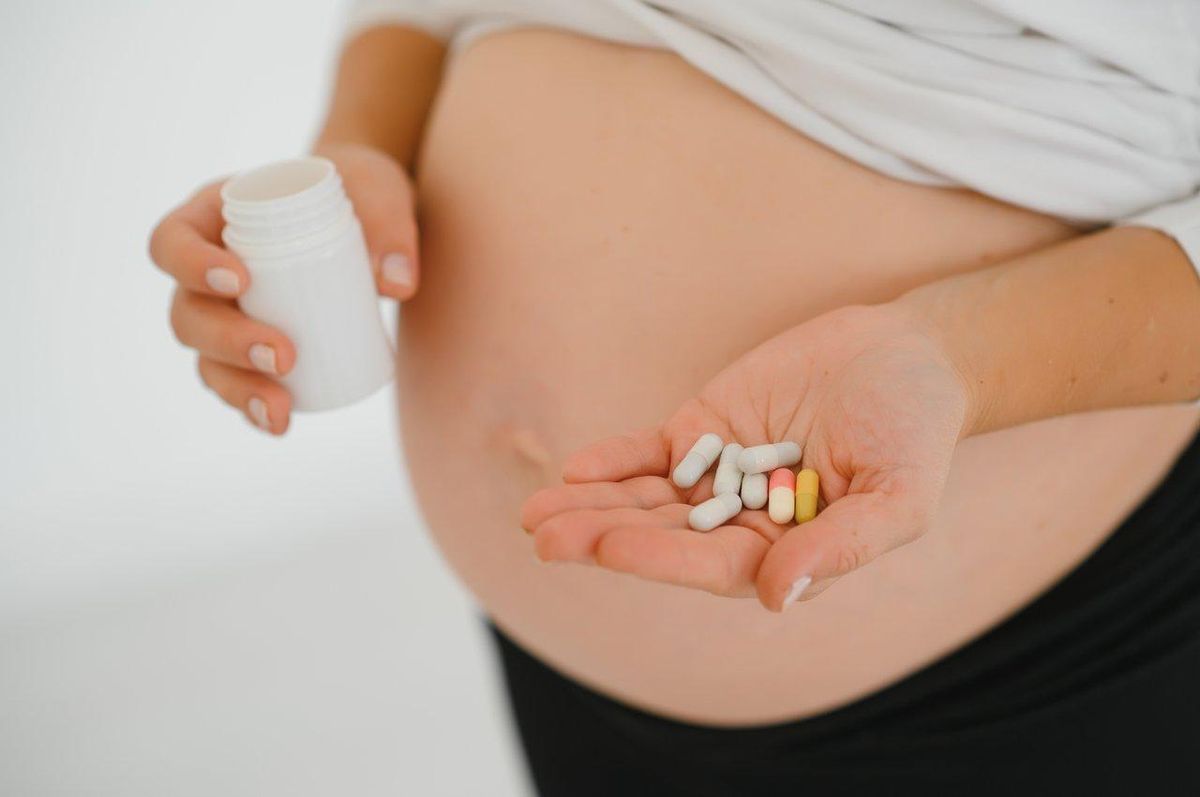 Boîte de compléments alimentaires avec vitamines et minéraux essentiels pour la grossesse, notamment vitamine B9, choline, zinc, magnésium et vitamine D3.