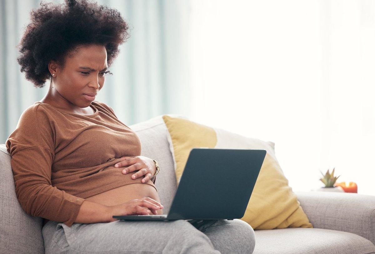 Femme freelance enceinte planifiant son congé maternité avec son ordinateur et ses notes de organisation.
