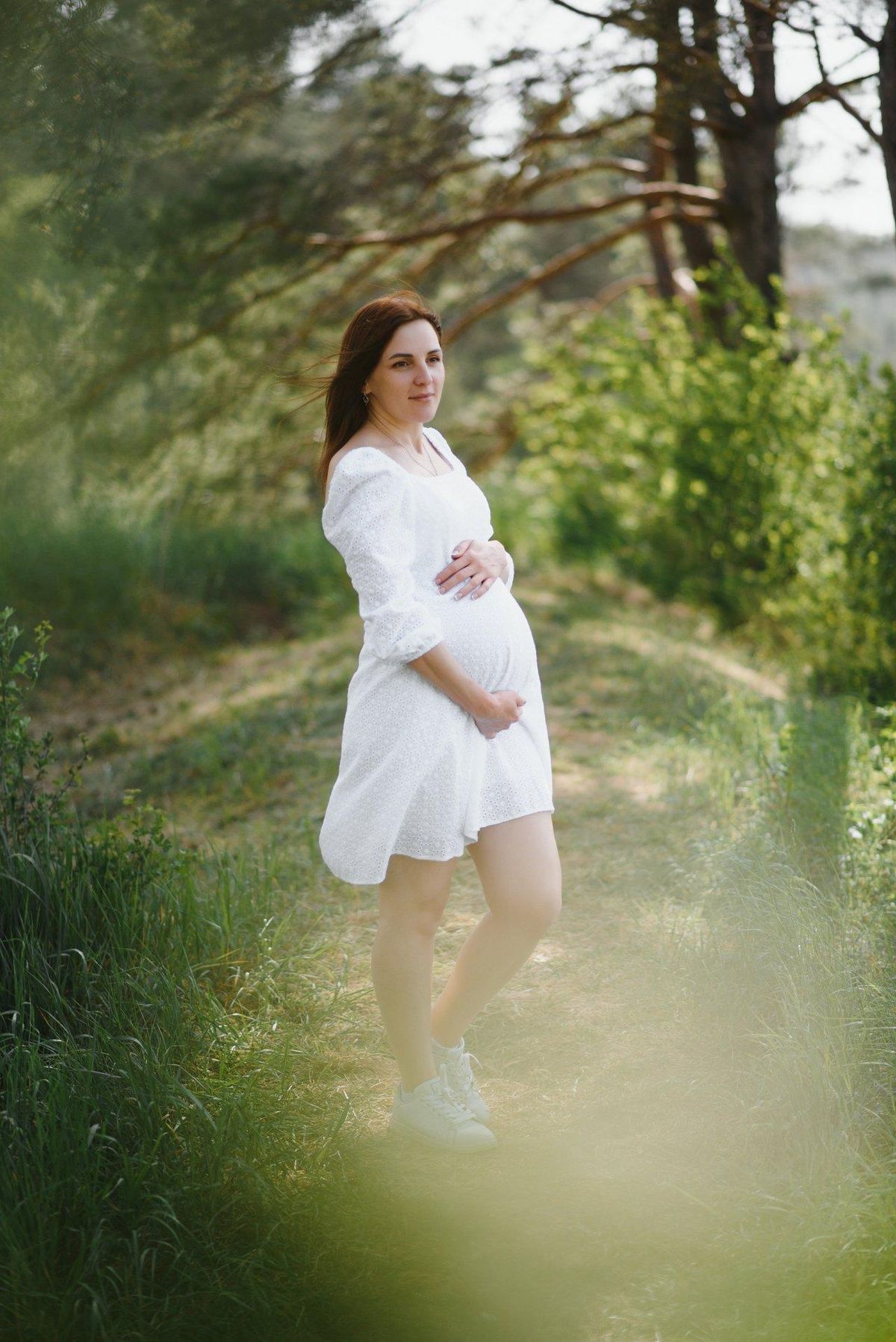 Sérénité du premier trimestre : une future maman rayonne au cœur de la nature.