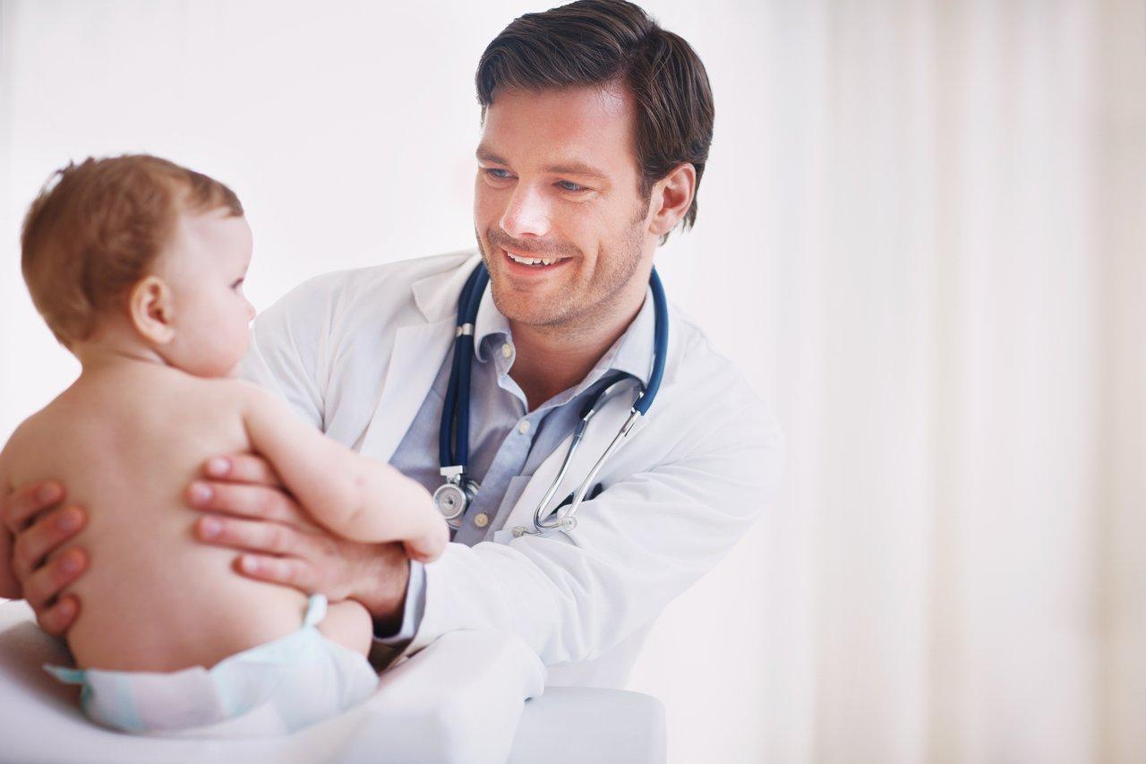 Un bébé souriant lors d’un contrôle pédiatrique, essentiel pour suivre son développement et son poids.